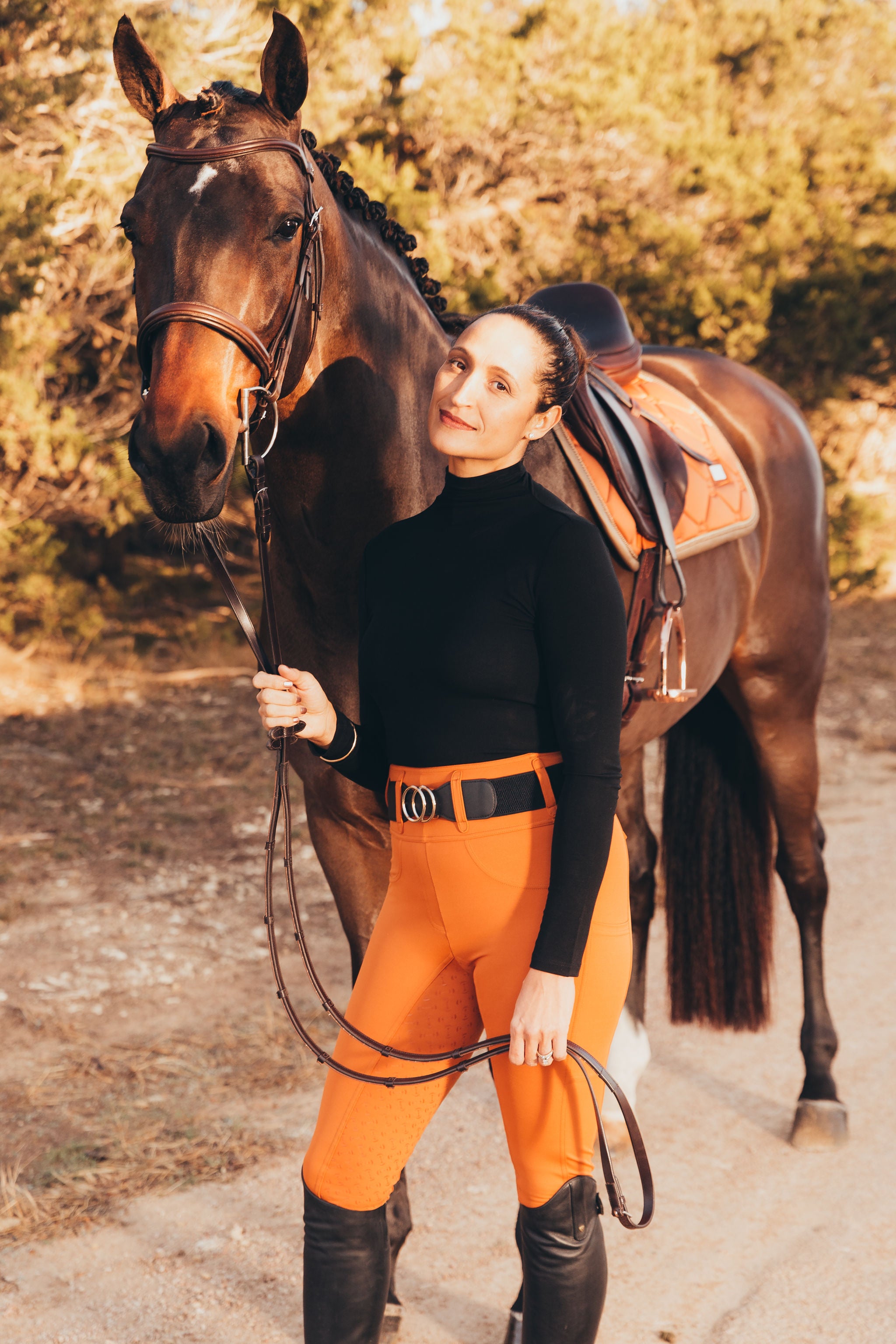 Canter Culture's glazed ginger riding tights are bright orange in the sun and matches well with Equestrian Stockholm Bronze Gold.